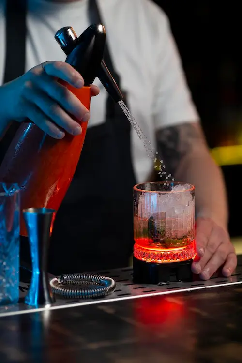 Barman servant un cocktail au siphon
